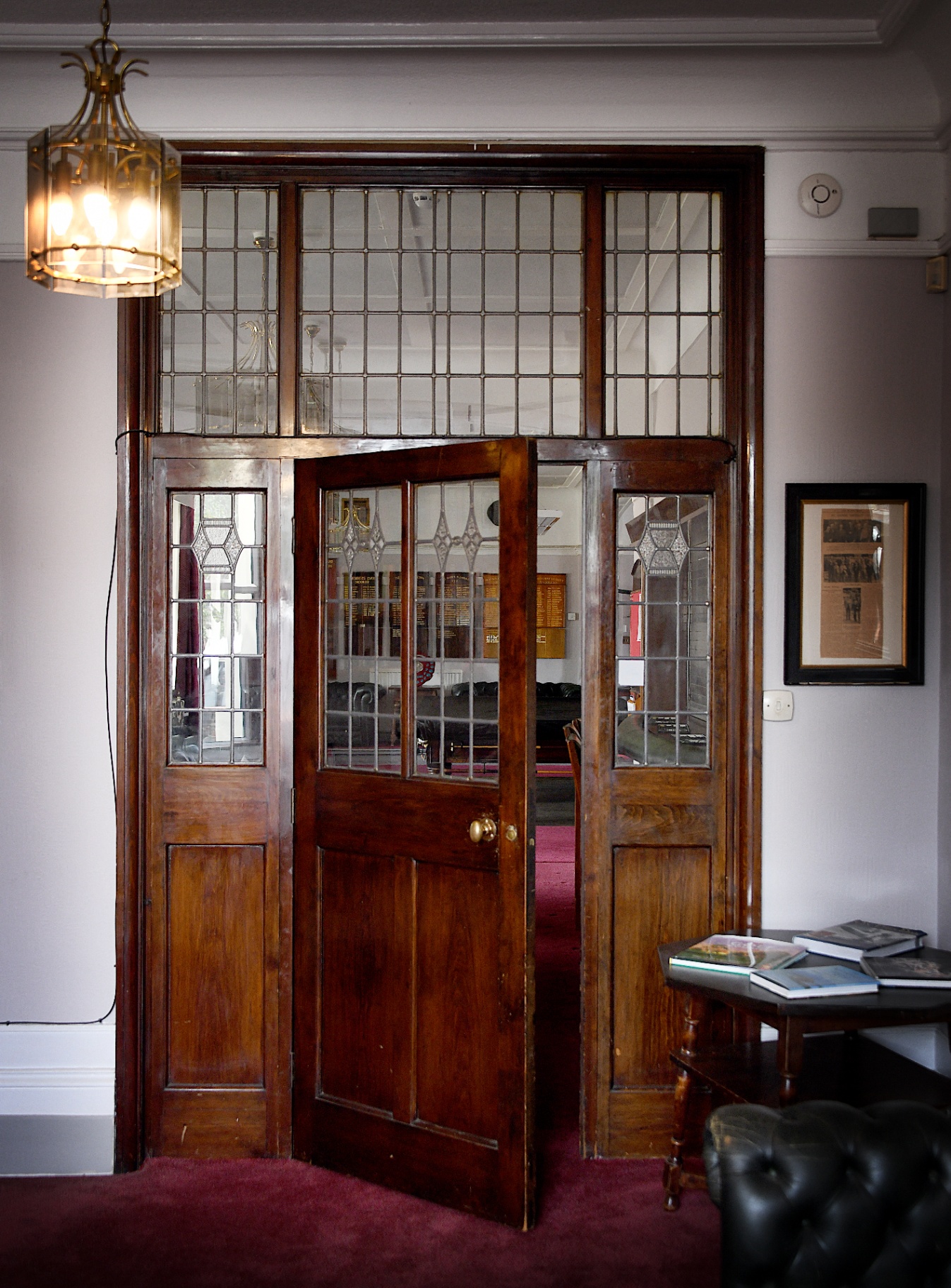 The club's leaded glass double doors, one of them standing open above a red carpet
