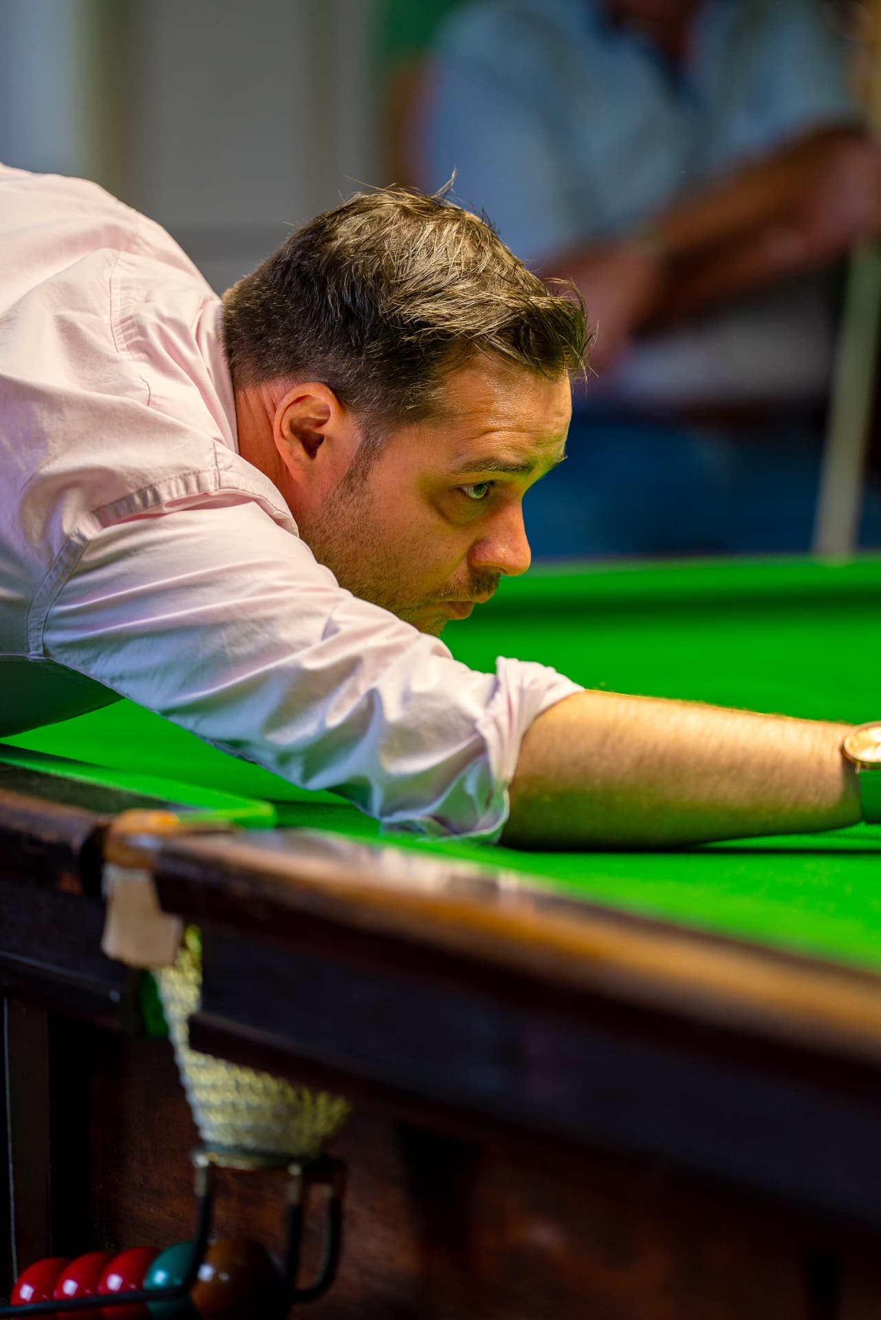 A player down on the cue, lining up a shot across the snooker table.