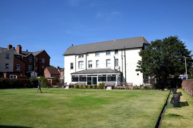 The District Club's bowling green in summer with the white clubhouse and conservatory rising behind it.