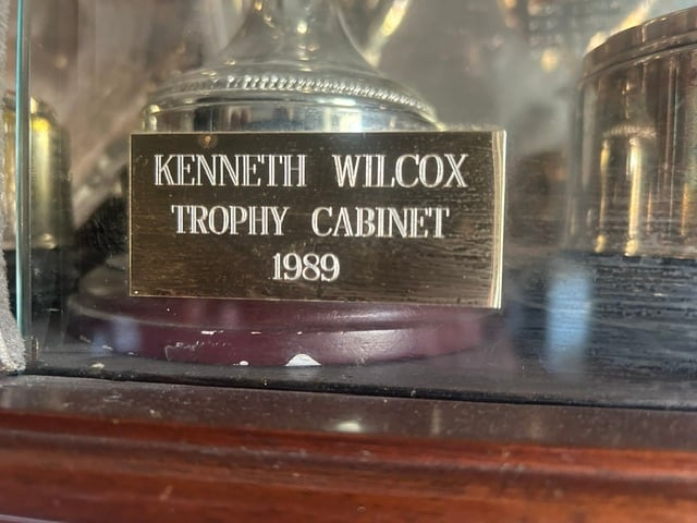 Brass plate reading Kenneth Wilcox Trophy Cabinet 1989 inside the trophy cabinet