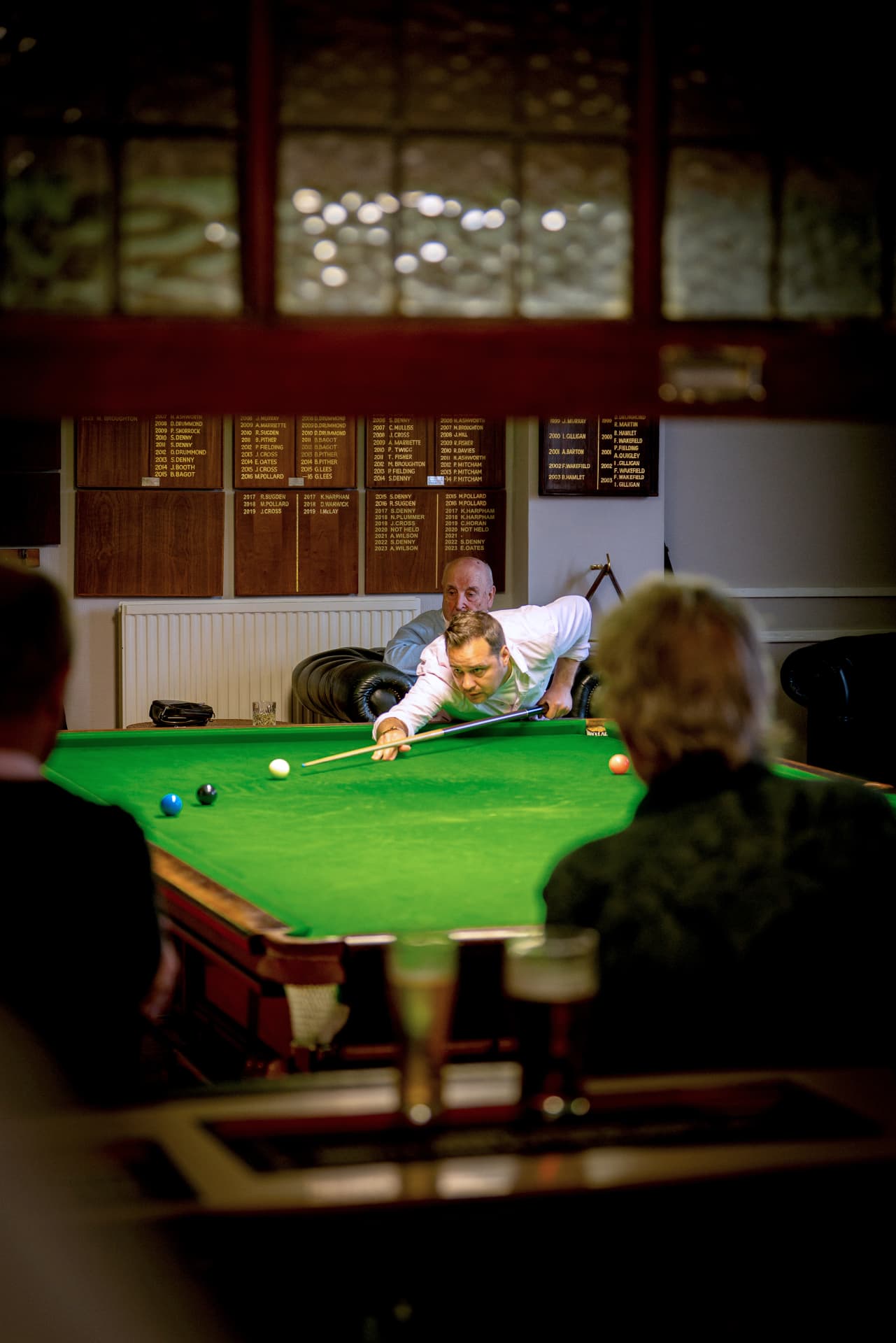 A snooker match in progress beneath the club honours boards.